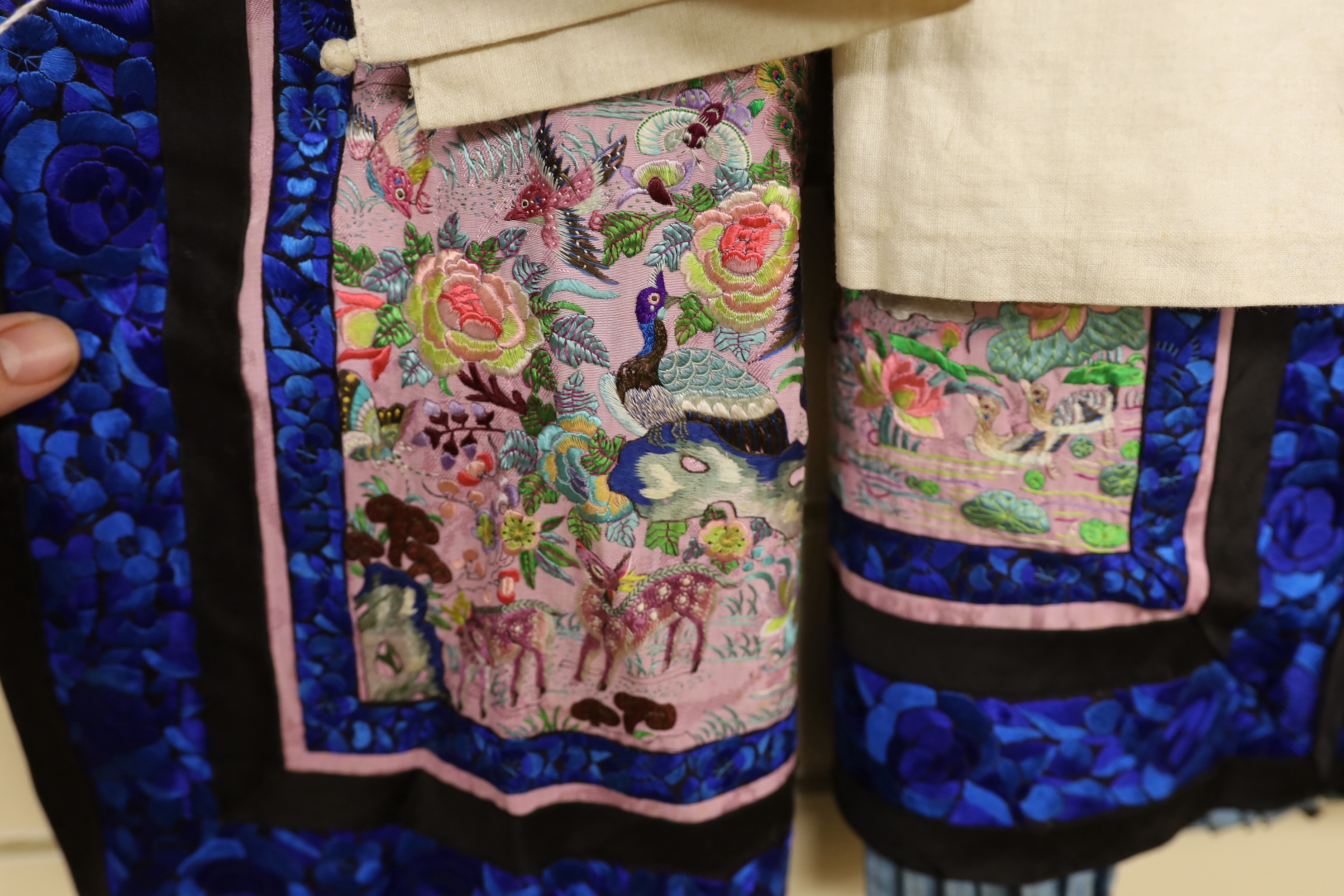 Two Chinese late 19th century lilac silk damask skirts, with polychrome silk front panels embroidered with birds, animals and pagoda, with blue embroidered border panels on black silk.